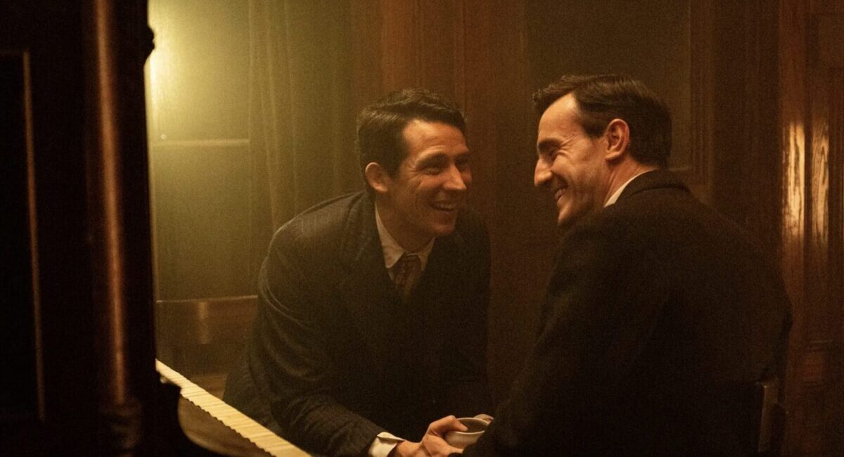 Two men laughing in suits in a dark bar